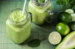 Green smoothie on green background made by avocado, lemon and kiwi.
