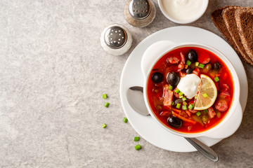 Wall Mural - Traditional Russian meat soup Solyanka in bowl on grey stone background. Top view. Copy space.