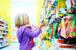 © Petr Bonek - Adorable child blond girl select sweets on shelves in supermarket