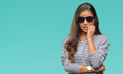 Poster - Young beautiful arab woman wearing sunglasses over isolated background looking stressed and nervous with hands on mouth biting nails. Anxiety problem.