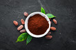 Cocoa powder in a bowl and cocoa bean. On a black background. Top view. Free copy space.