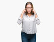 © Krakenimages.com - Young caucasian beautiful business woman wearing glasses over isolated background covering ears with fingers with annoyed expression for the noise of loud music. Deaf concept.