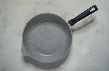 Grey stone pan on grey table. Top view.