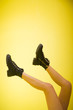 © primipil - Female legs in black shoes on a yellow background