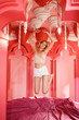 © primipil - Young girl jumping on the bed with pink lilac linen