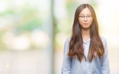 Sticker - Young asian business woman wearing glasses over isolated background with serious expression on face. Simple and natural looking at the camera.