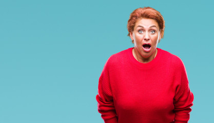 Poster - Atrractive senior caucasian redhead woman wearing winter sweater over isolated background afraid and shocked with surprise expression, fear and excited face.