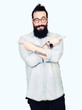 © Krakenimages.com - Young hipster man with long hair and beard wearing glasses Pointing to both sides with fingers, different direction disagree