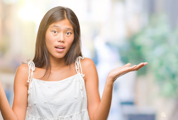 Sticker - Young asian woman over isolated background clueless and confused expression with arms and hands raised. Doubt concept.