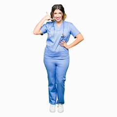 Poster - Young adult doctor woman wearing medical uniform smiling doing phone gesture with hand and fingers like talking on the telephone. Communicating concepts.