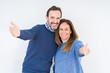 © Krakenimages.com - Beautiful middle age couple in love over isolated background looking at the camera smiling with open arms for hug. Cheerful expression embracing happiness.