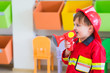 © weedezign - Caucasian boy kid dress up to fireman and use speaker at roll play classroom,Kindergarten preschool education concept.