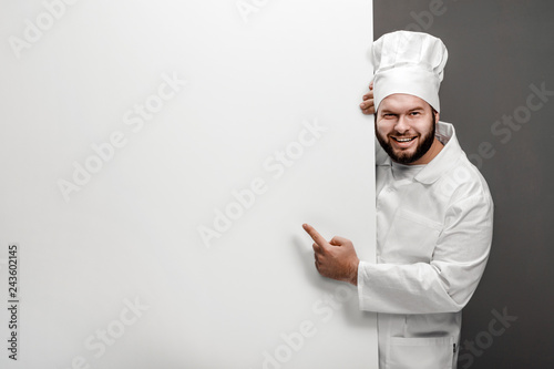 Cuadros en Lienzo Overweight professional cook smiling and looking at camera while pointing at emp
