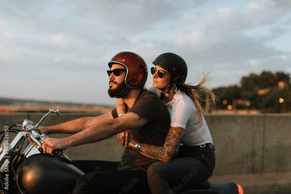 Biker couple riding down the road in the sunset - obrazy, fototapety, plakaty 