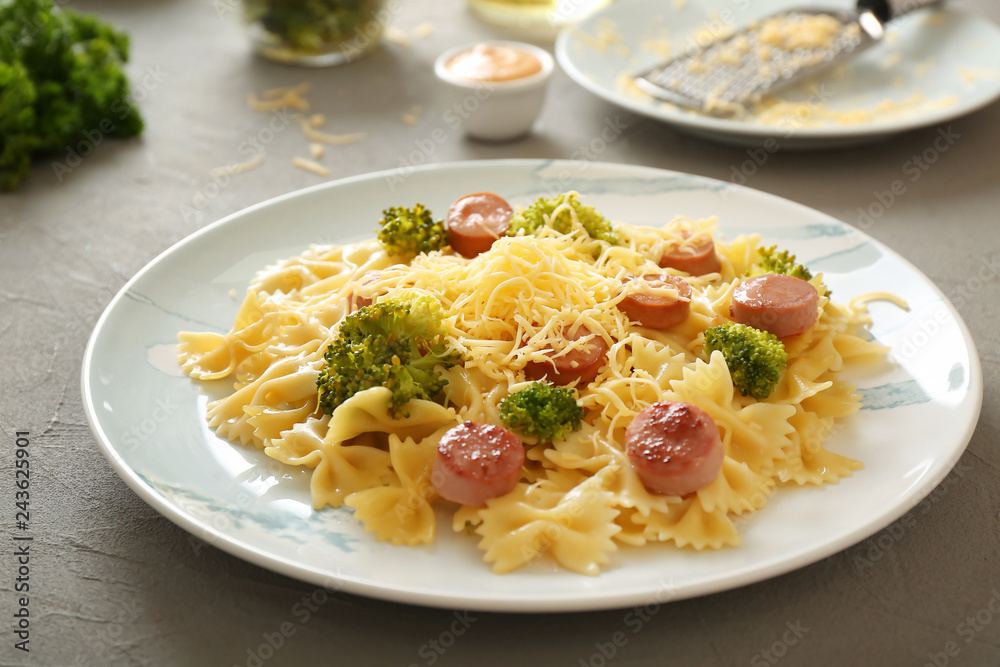 Plate with delicious pasta and sausage on grey table