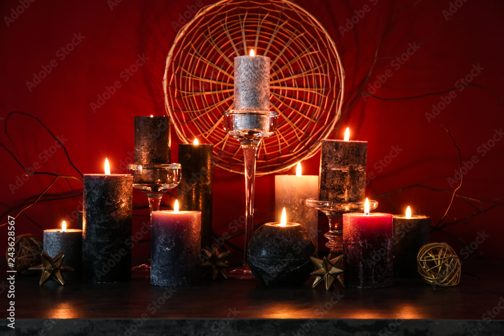 Beautiful burning candles with golden decor on dark table