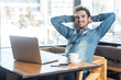 © khosrork - Have a break! Portrait of handsome successful bearded young freelancer in blue jeans shirt are sitting in cafe and having a rest, holding hands behind head with toothy smile and looking at camera.