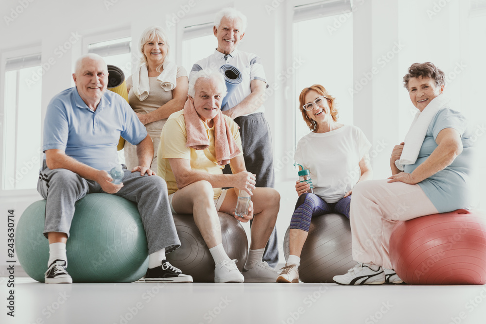 Group of active seniors sitting on exercising balls in modern fitness center after sport's training - obrazy, fototapety, plakaty 