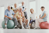 Fototapeta  - Group of active seniors sitting on exercising balls in modern fitness center after sport's training