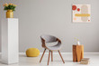 © Photographee.eu - Pile of books next to wooden coffee table with flower in vase and trendy grey chair and yellow pouf