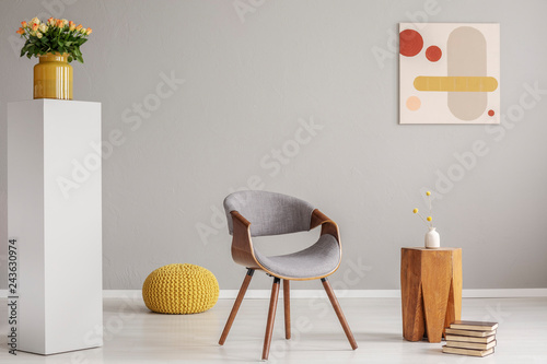 Fotografía Pile of books next to wooden coffee table with flower in vase and trendy grey ch