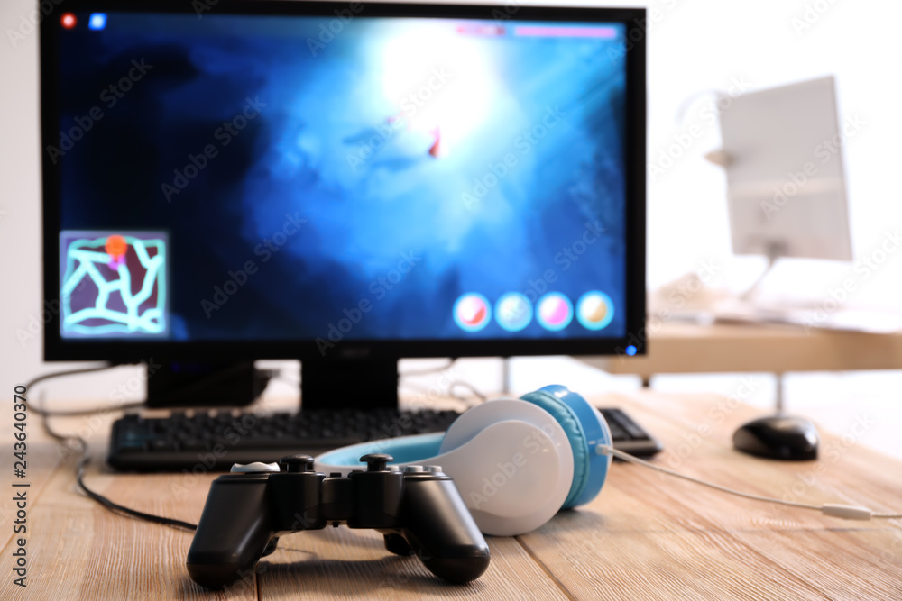 Computer, game pad and headphones on table in club