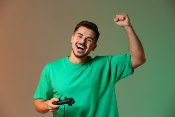 Sticker - Happy young man after winning video game on color background