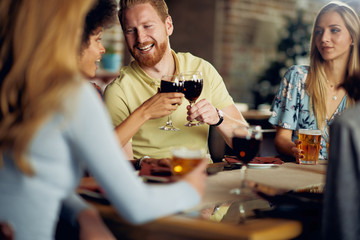 Wall Mural - Friends making a toast while sitting in restaurant. Multi-ethnic group.