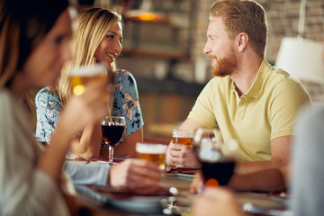 Wall Mural - Friends chatting and drinking alcohol while  sitting at restaurant.