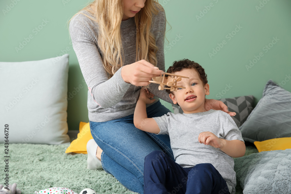 Young mother with cute little son playing at home