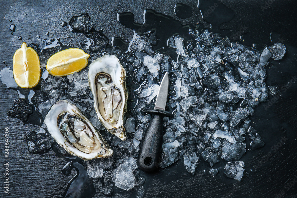 Tasty raw oysters with ice and lemon on dark background