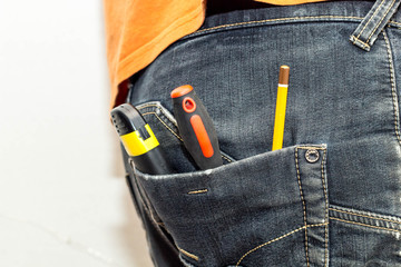 Engineering work tool in the back pocket of the jeans. pencil screwdriver hammer and utility knife