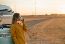 Young Woman Drinking By Campervan During Sunset