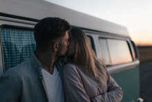 Young Couple Kissing  By Campervan During Sunset