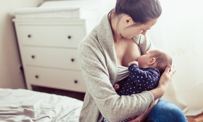 young mother breastfed her baby girl. mother breastfed baby at the bedroom.