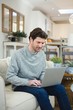 © WavebreakMediaMicro - Man using laptop in living room