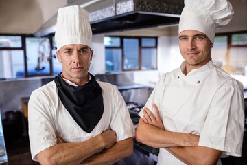 Wall Mural - Two male chefs standing with arms crossed in kitchen