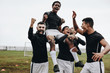 Soccer players celebrating success by lifting a teammate on shou