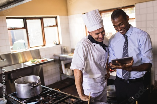 Fotografía Male manager and chef using digital tablet in kitchen