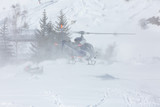 Fototapeta Niebo - Rescue helicopter during a snow storm in the mountains