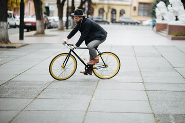 Young hipster bearded man riding bicycle to work on urban street