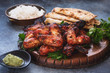 Indian tandoori chicken wings served with pilau rice and garlic naan , selective focus