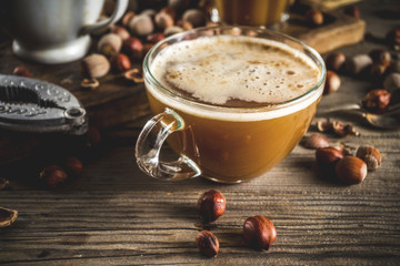 Wall Mural - Homemade hazelnut coffee latte or cappuccino, rustic wooden background with hazelnuts, three coffee cups copy space