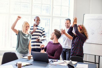 Smiling coworkers cheering together during an office meeting