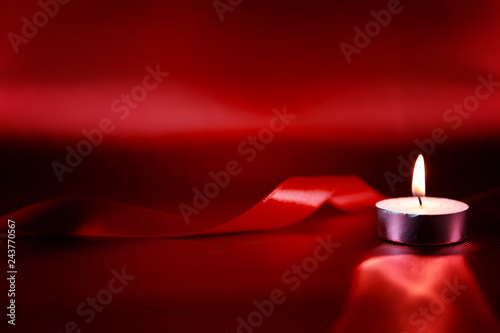Obraz Dibond Valentine's day concept. Candle in candlestick with red ribbon on red shiny background