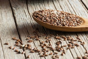 Heap of Flax seeds or linseeds in spoon on wooden backdrop. Flaxseed or linseed concept. Flax seed dietary fiber background