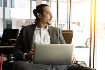 young indian business male on laptop, phone and coffee at a cafe