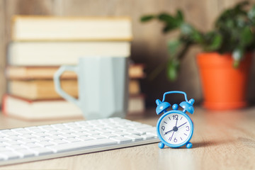 Alarm clock and keyboard on the office desk. Office concept, work day, hourly pay, work schedule