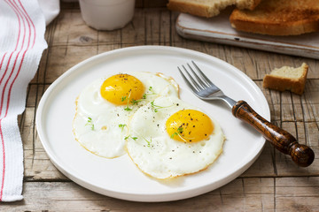 Breakfast of fried eggs, bread toasts and coffee on a wooden table. Rustic style.