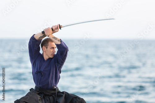 Fotografie, Obraz Young Iaido fighter master of martial arts exercises in a concentrated manner ho